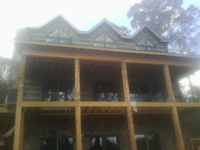 Dormers and porch framing on a large log home under construction — Roof Coating work by our crew in Graham